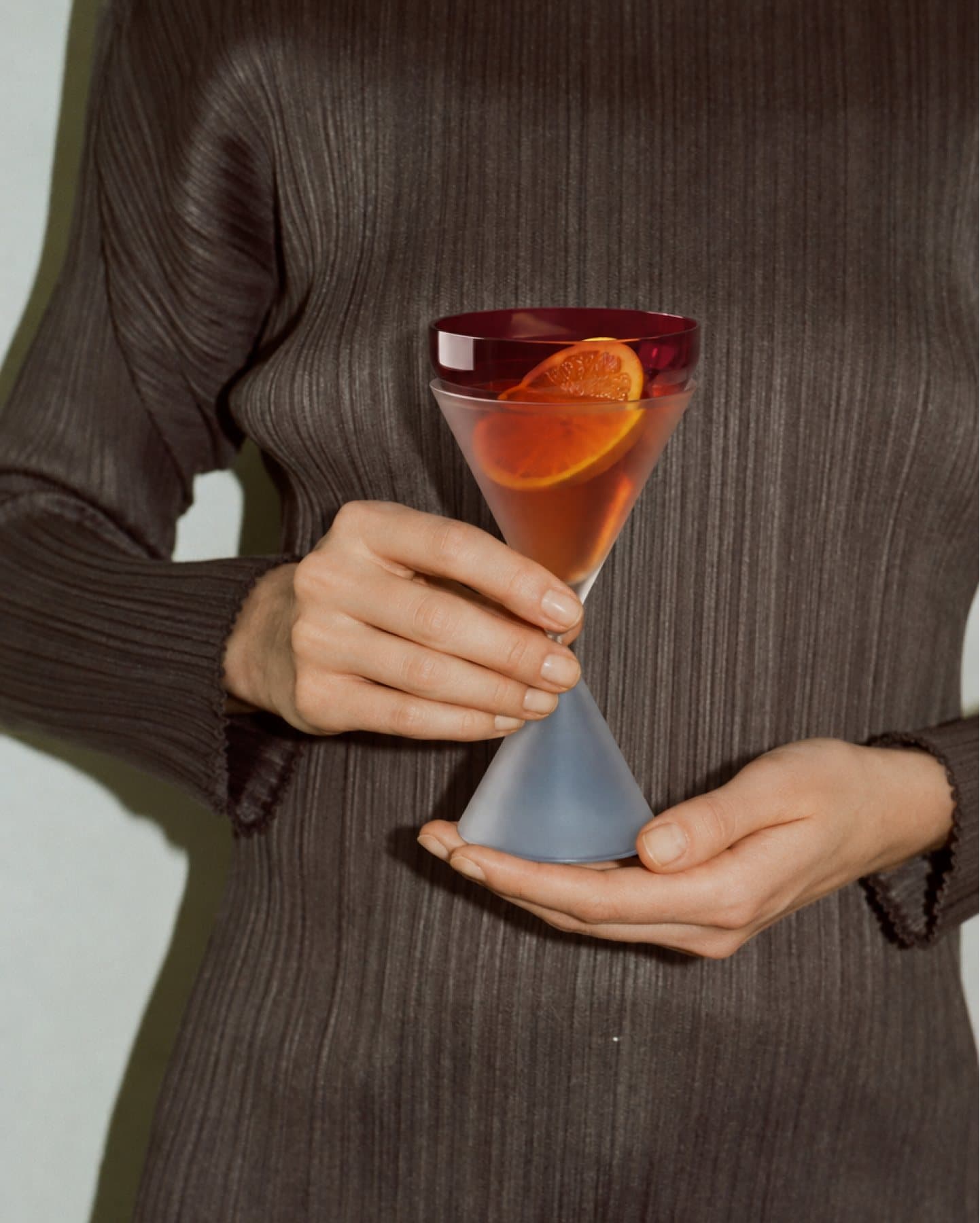Alguien sostiene una copa de Conversa con un coctel de naranja