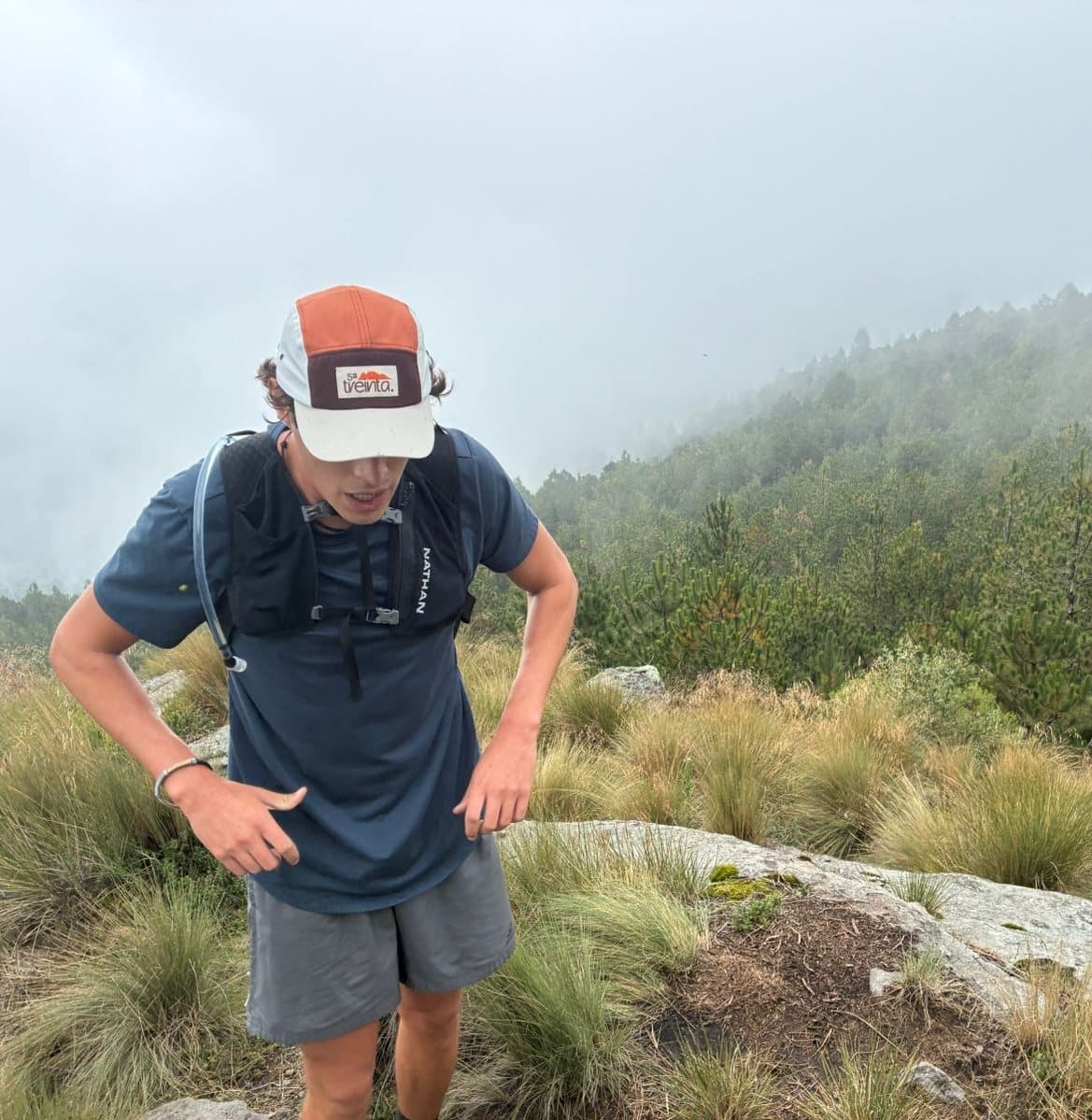 Someone wearing the cap on a misty hill, looking down at the grass