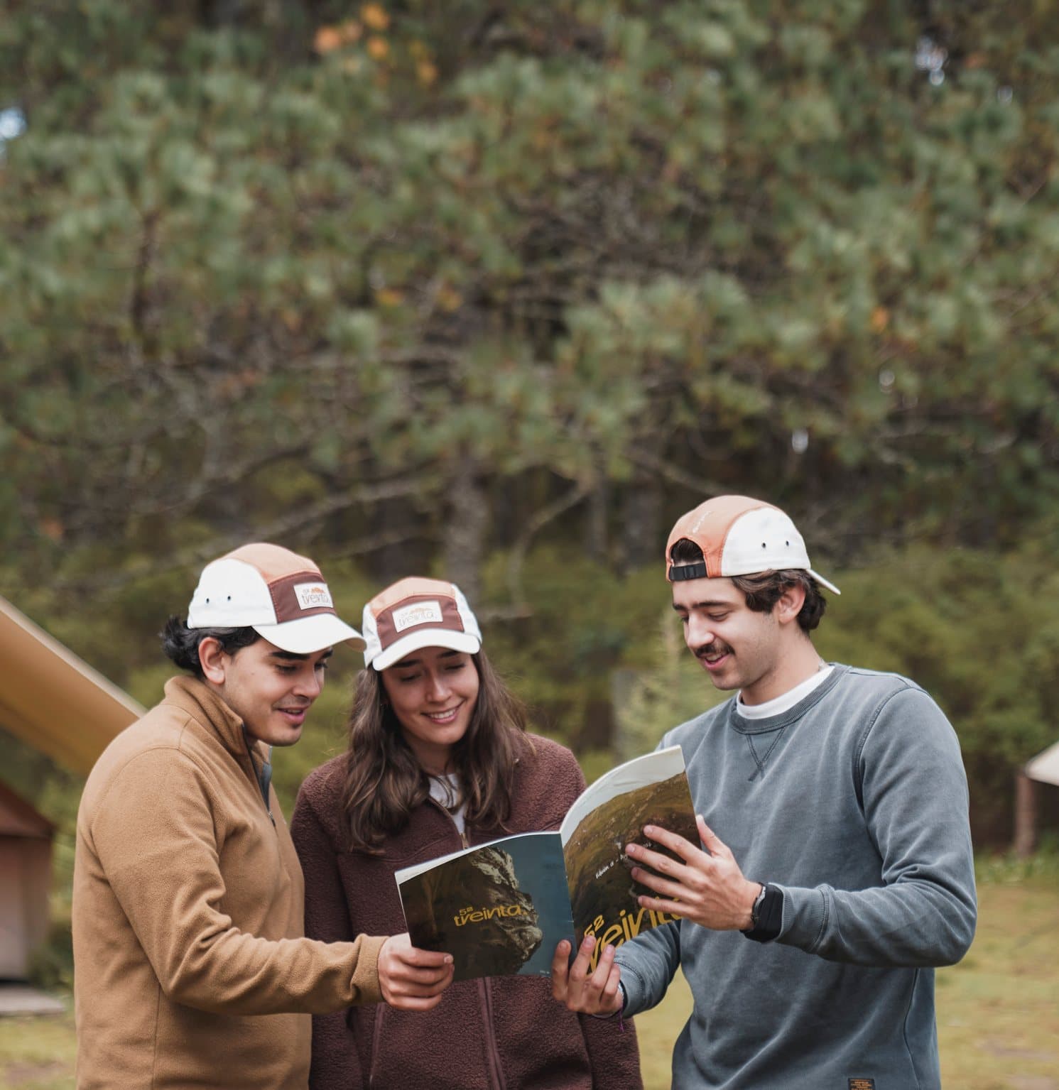 Three friends wearing the cap read the magazine in the forest