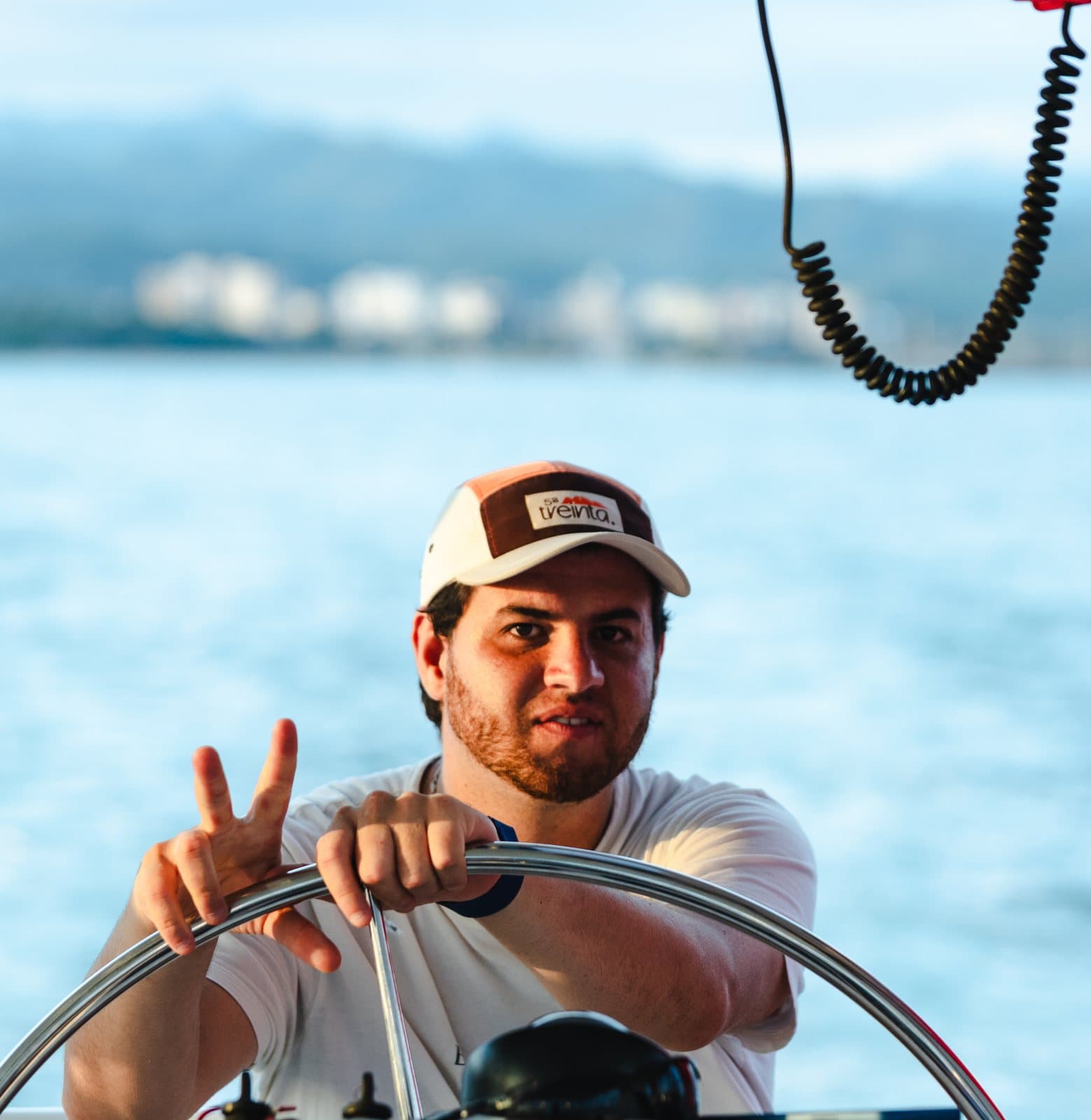 Someone wearing the cap steers a sailboat on the lake